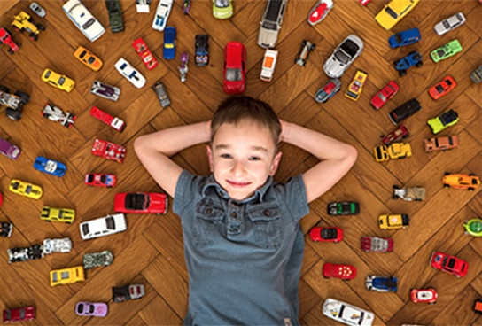 a happy boy surrounded by his toy cars & hot wheels